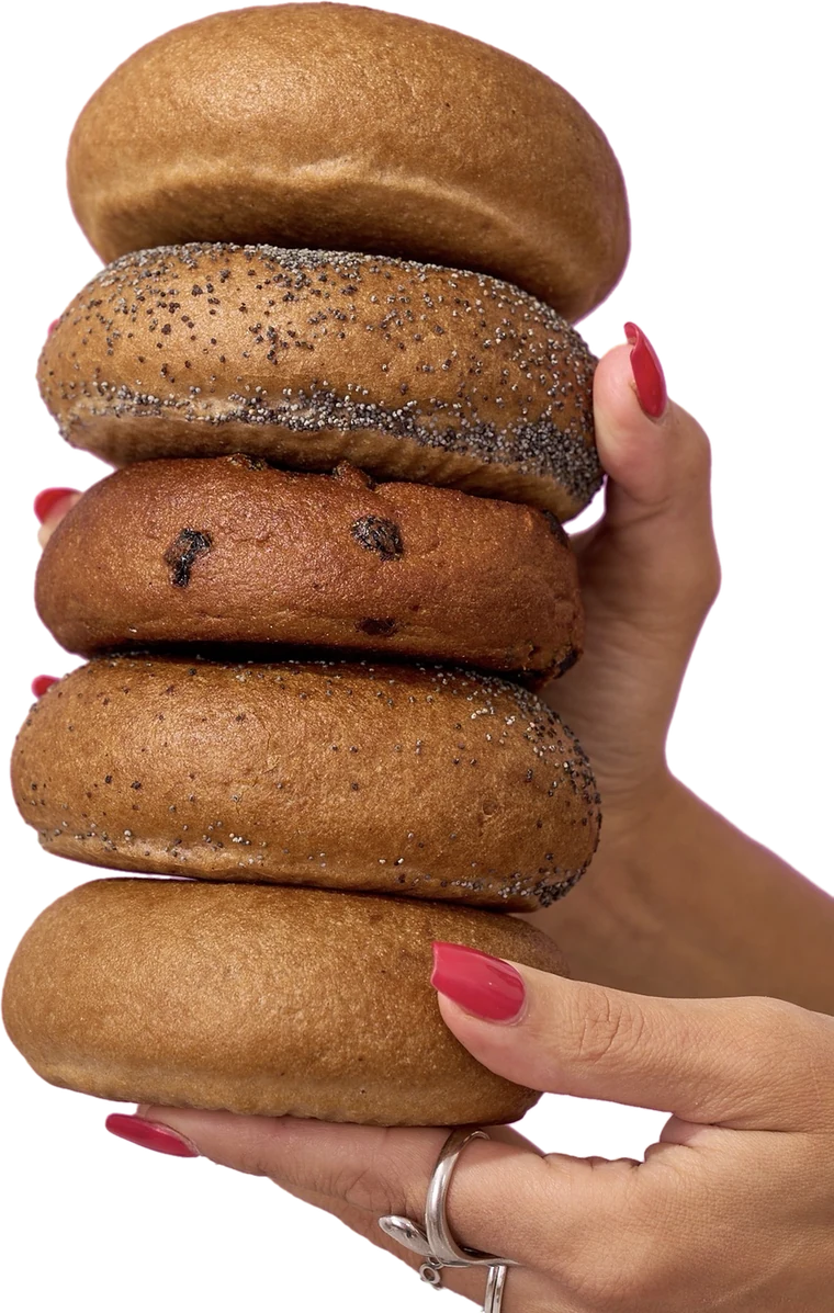 A stack of five Good Grain sourdough bagels held in two hands